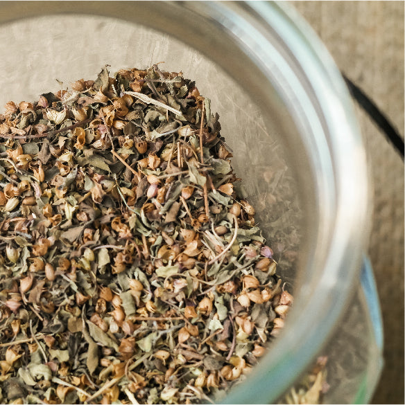 Top view of a glass jar filled with dried basil spice mix