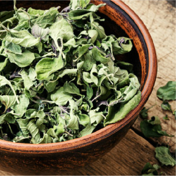 Dried marjoram leaves in a rustic brown ceramic bowl.