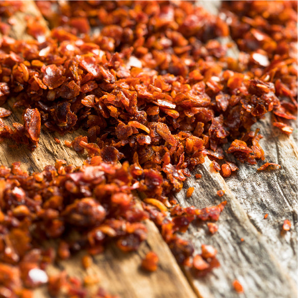 Crushed red pepper flakes scattered on a weathered wooden surface