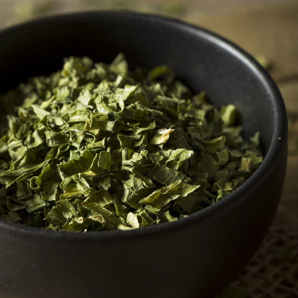 Chopped dried chives in a dark bowl