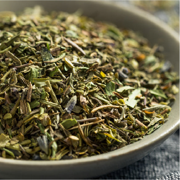 Close up of chopped Herbes de Provence in a metal bowl showing green herb pieces