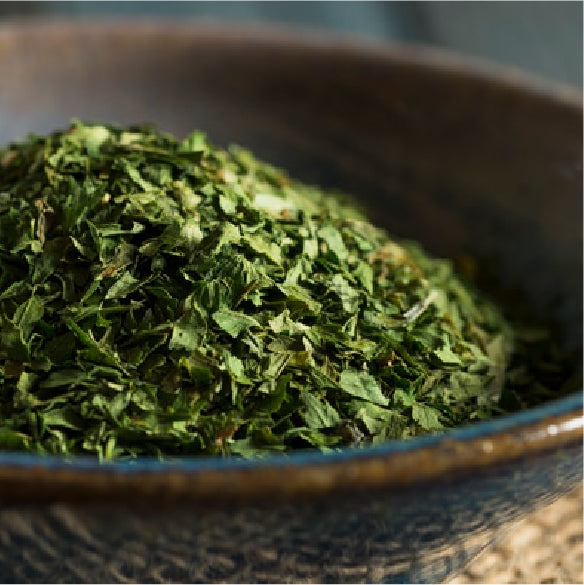 Chopped dried parsley heaped in a rustic blue bowl